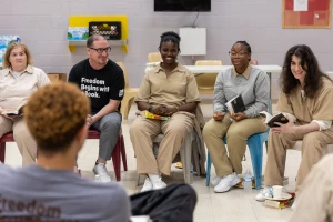 Inside Literary Prize book discussion at Edna Mahan Correctional Facility. Women wearing khaki prison uniforms sit in a circle with Freedom Reads team discussing books