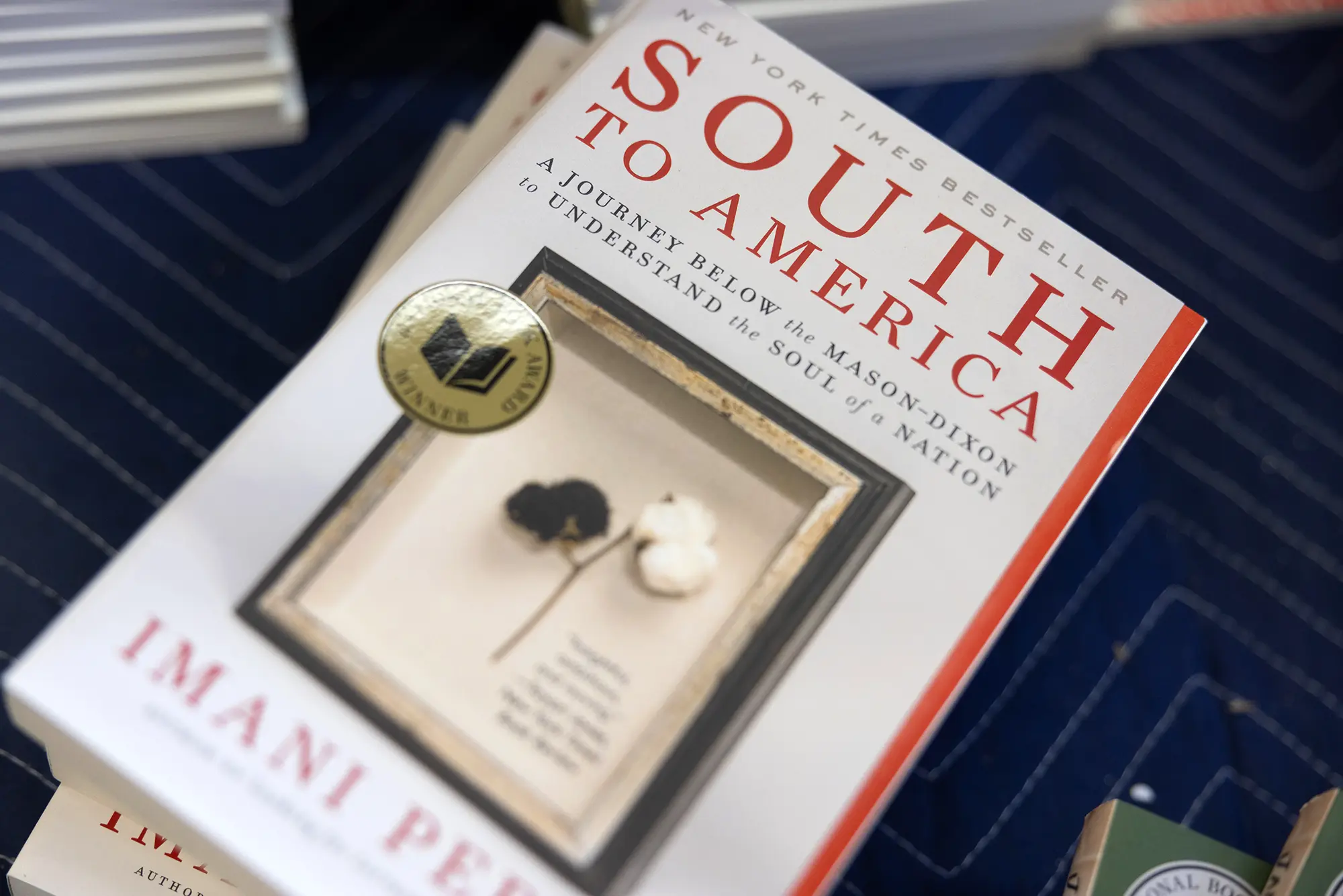 Stacked copies of the book South to America: a Journey Below the Mason-Dixon to Understand the Soul of a Nation by Imani Perry, a current Inside Literary Prize finalist.