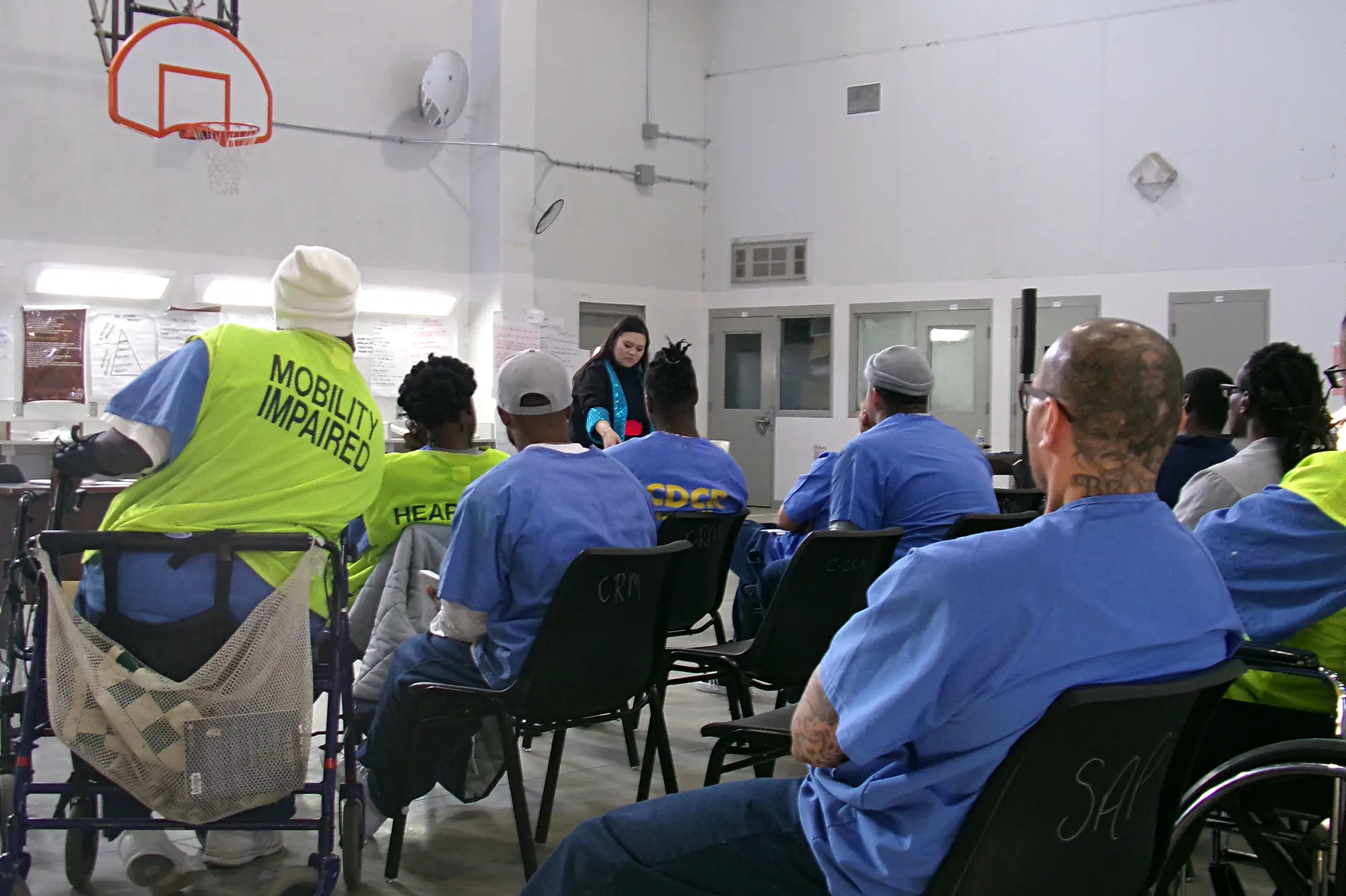 The audience at the Correctional Training Facility in California lean in as they watch Gaosong Heu, from Literature to Life organization, perform The Latehomecomer: A Hmong Family Memoir by Kao Kalia Yang.